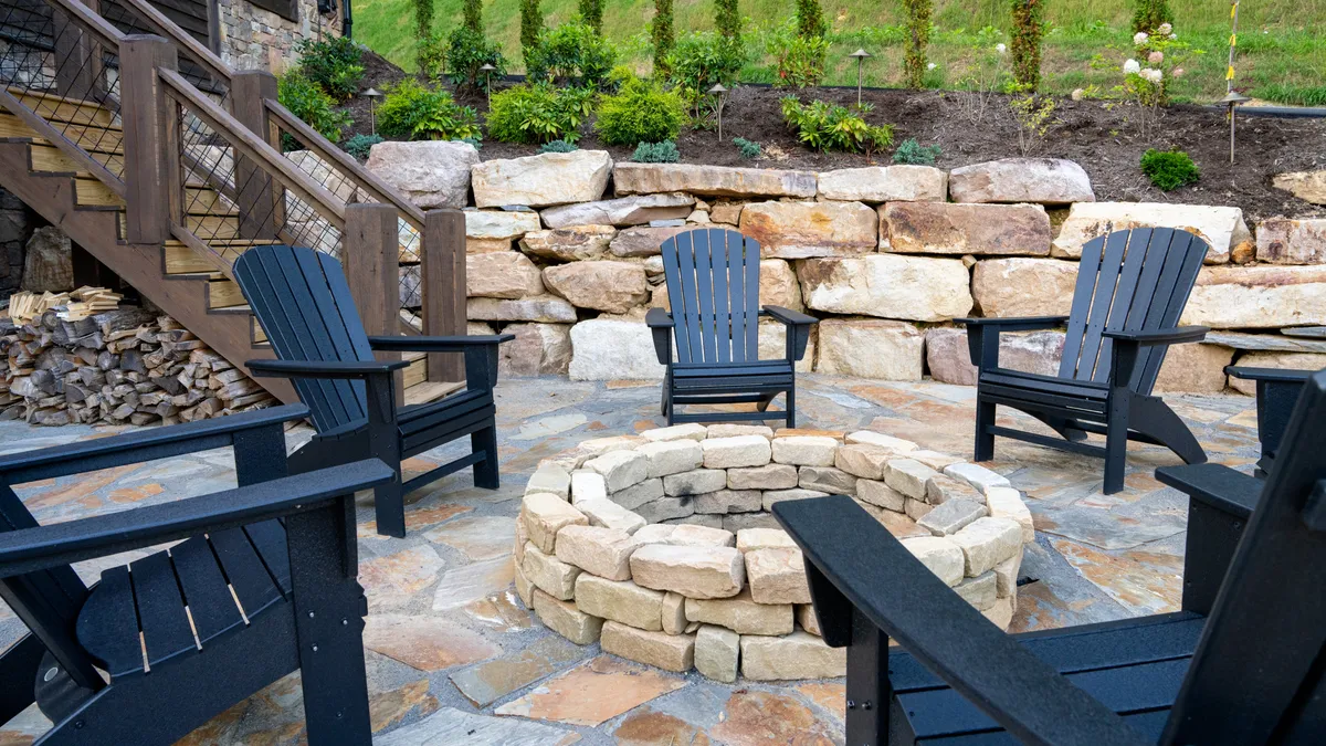 A cozy firepit setup with adirondack chairs arranged around a stone firepit, backed by landscaped gardens and thoughtful lighting. The setting is perfect for evening gatherings, storytelling, and enjoying the fresh mountain air after dark.
