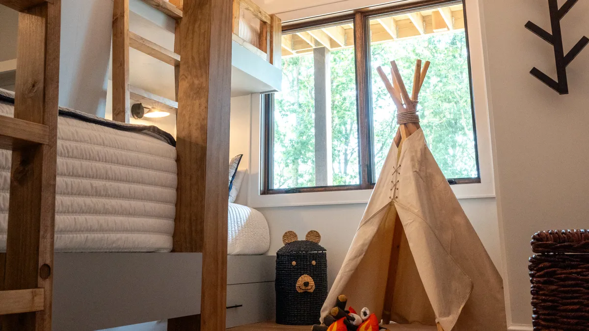 A whimsical bunk room featuring a teepee, bunk bed, playful stuffed animals, and cozy decorative touches. The room feels imaginative and inviting, perfect for children or young-at-heart guests.